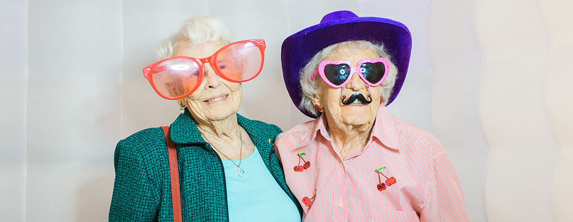 A couple ladies wearing silly glasses and hats
